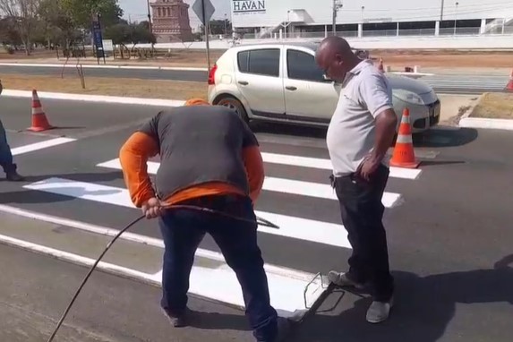 Equipe da Zeladoria Urbana realizando a revitalização da sinalização em frente ao Ambulatório de Atenção a Saúde - AMAS